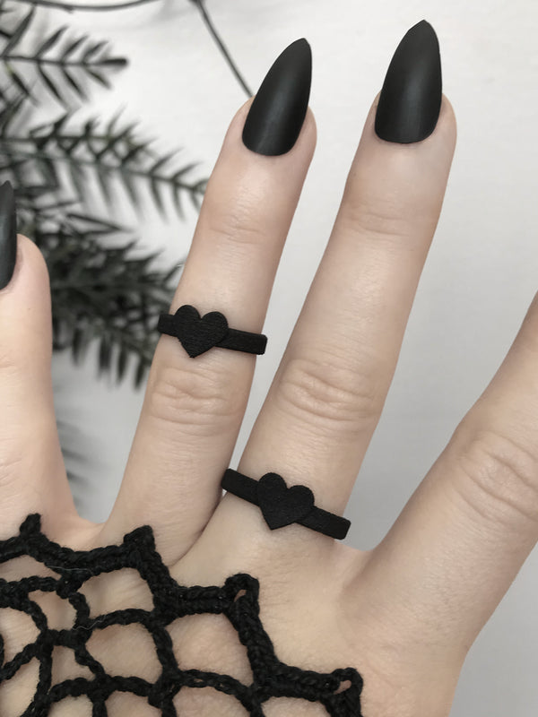 Cute 3d printed black heart ring displayed on a gothic model hand with long black nails