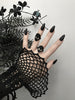 Zoomed out view of 2 black rings with classic 90s alien faces displayed on gothic model's hand with long black nails and witchy black flowers. 3d printed jewelry by Hypnovamp.