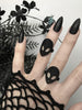 Black ring with classic 90s alien face displayed on gothic model's hand with long black nails and witchy black flowers. 3d printed jewelry by Hypnovamp.