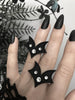 3 Matte black bat wing rings with white swarovski crystal stones, displayed on a gothic model's hand with long black nails. 3d printed jewelry by Hypnovamp.