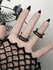 Backside view of 3 double banded matte black bat wing rings with white swarovski crystal stones, displayed on a gothic model's hand with long black nails. 3d printed jewelry by Hypnovamp.