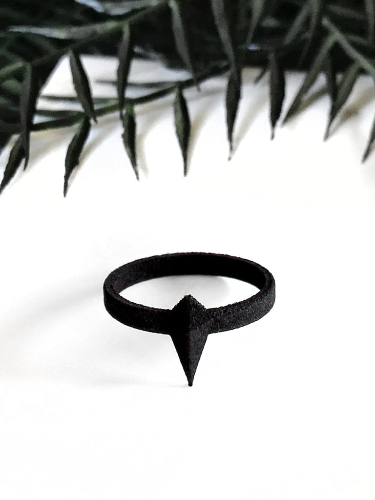 Matte black 3d printed goth ring with geometric pointy spike design, displayed on white background with  black foliage border.