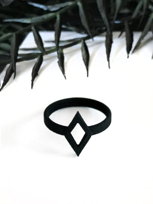 Bold graphic 3d printed black ring with diamond shaped outline design, displayed on white background with gothic black foliage border.