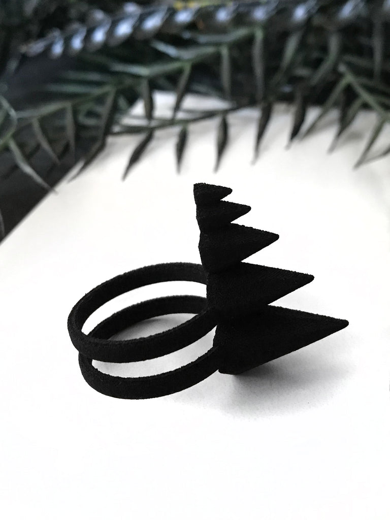Side view, 3d printed black self defense ring with pyramid spikes, displayed on a white background with black foliage. Punk/gothic jewelry by Hypnovamp.
