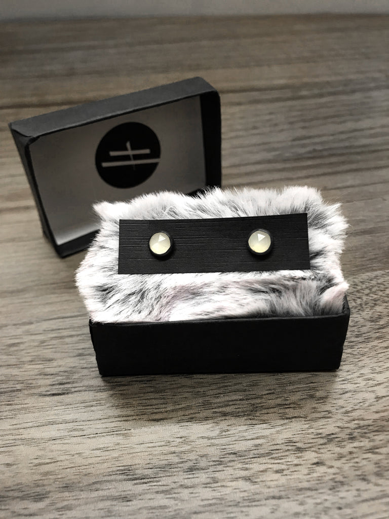 Witchy style stud earrings featuring oxidized sterling silver & rose-cut white moonstone. Displayed in black jewelry box with grey fur. Minimalist gothic jewelry handmade in Salem, MA by jewelry designer Hypnovamp.