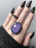 Light purple faceted rose quartz crystal ring displayed on a witchy model hand with long black nails and a black ring. Handmade silver glow in the dark jewelry by Salem, Massachusetts artist Hypnovamp.