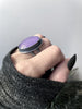 Side view of lavender faceted rose quartz crystal ring displayed on a gothic model hand with long black nails and grey sweater. Handmade silver glow in the dark jewelry by Salem, Massachusetts artist Hypnovamp.