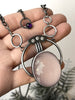 Handmade silver space-age art deco necklace with faceted rose quartz, amethyst, and three white crystals, displayed in a hand. Retro witchy jewelry made by Salem, Massachusetts artist Hypnovamp.