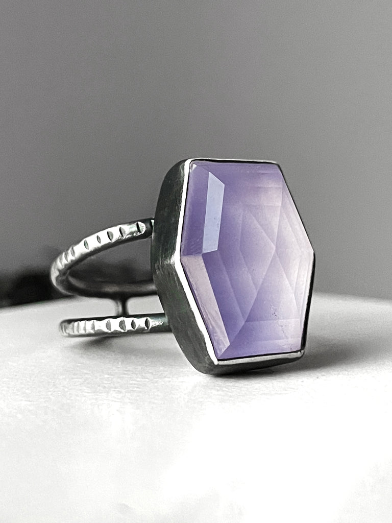 Handmade silver glow ring featuring a step cut quartz hexagon with a pale lavender color displayed on a white and grey background. High quality glow in the dark jewelry made by witchy Salem MA jewelry designer Hypnovamp.