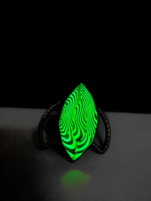 Night view of handmade silver glow ring with trippy op art pattern under a marquise shaped stone, set on a silver crescent moon. High quality glow in the dark jewelry made in Salem, MA by artist Hypnovamp.