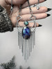 Handmade silver necklace featuring apex amethyst & blue labradorite gemstones set on a silver moon with chain fringe, held in a gothic model hand with long black nails.