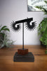 Black spiky hoop earrings displayed on an earring stand with plants and ouija board in the background. Geometric 3d printed jewelry by Hypnovamp.